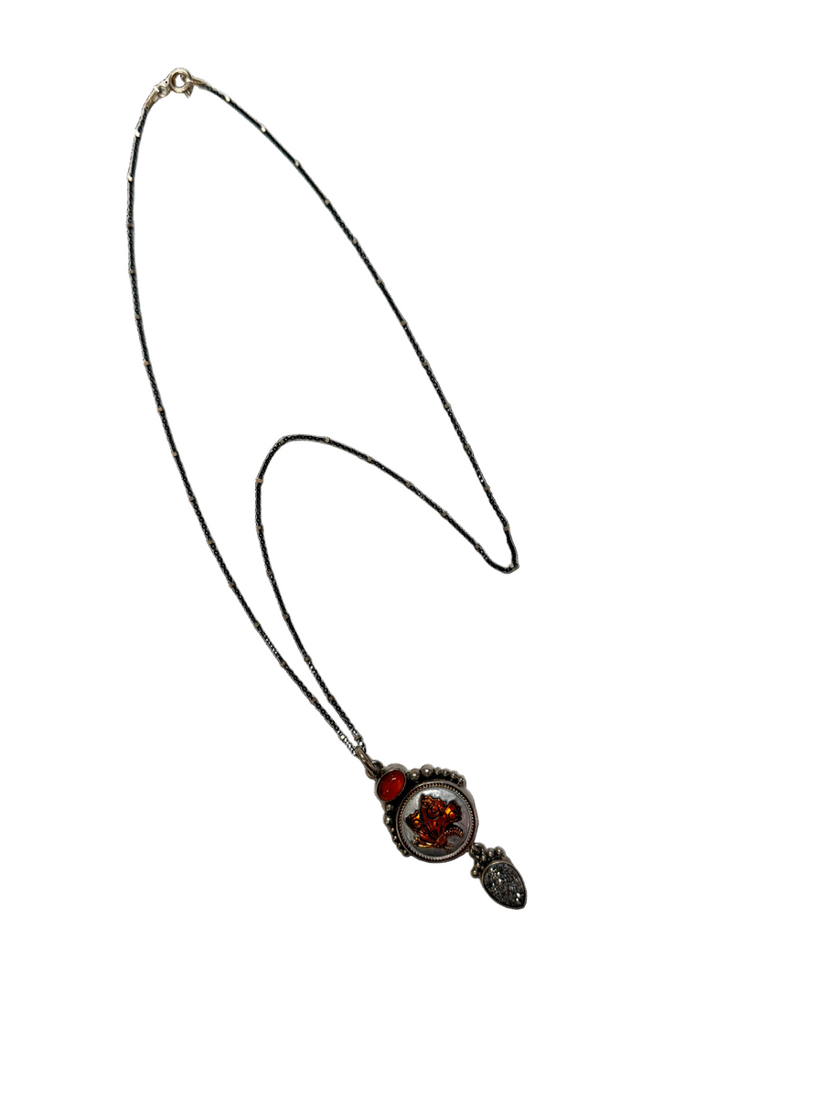 Necklace with a pendant featuring a red gemstone on a white background