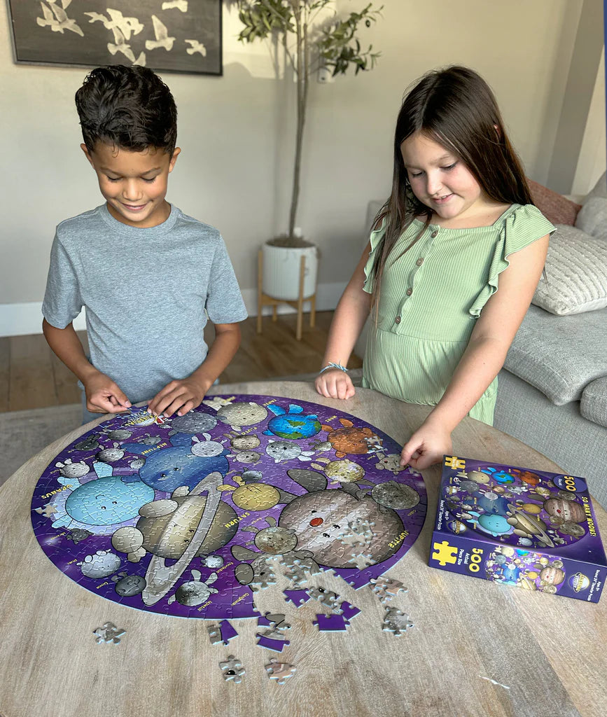 Two children working on a puzzle with space-themed pieces in a living room setting.